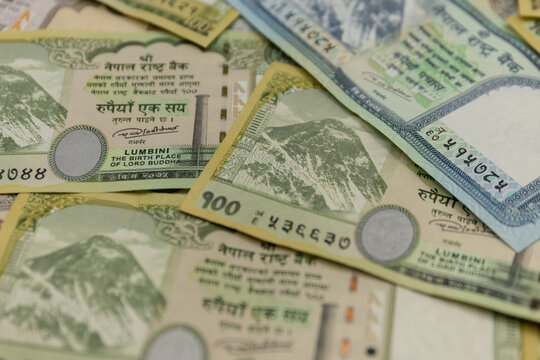 Nepalese rupee and United States dollar banknotes arranged together as physical paper currencies, displaying the distinctive colors, denominations, portraits, national symbols, architectural elements