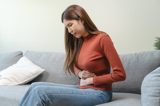 asian young woman intolerance hand in stomach ache, suffer from food poisoning, abdominal pain and colon problem
