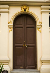 Obraz premium Heritage architecture and historical preservation, ornate brown wooden door with gold decorative molding on a classic colonial building facade