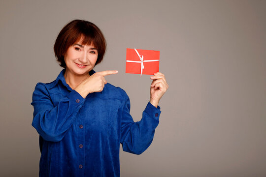 Senior woman pointing at red gift card reward