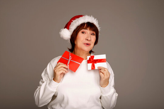 Senior woman holding christmas gifts wearing santa hat