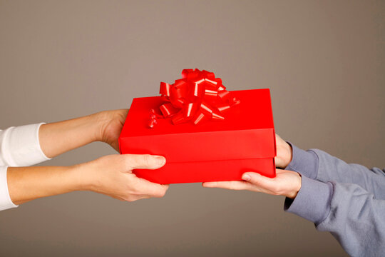 Hands exchanging a red gift box with ribbon