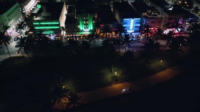 Aerial drone footage glides over Collins Avenue's vibrant neon landscape at night