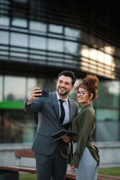 Happy business people smiling and taking selfie together in urban area