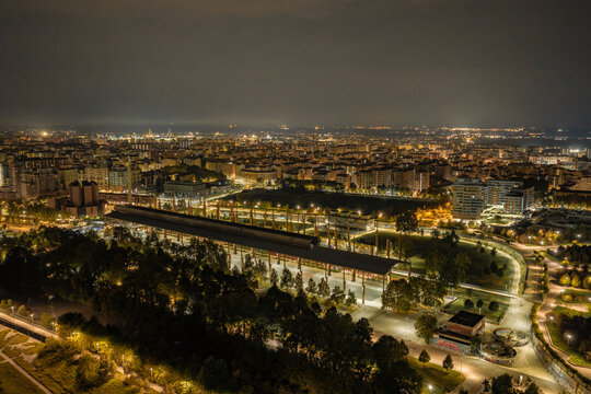 Aerial view of Parco Dora with its iconic industrial steel structures illuminated at night, surrounded by the urban landscape of Turin, Piedmont, Italy.