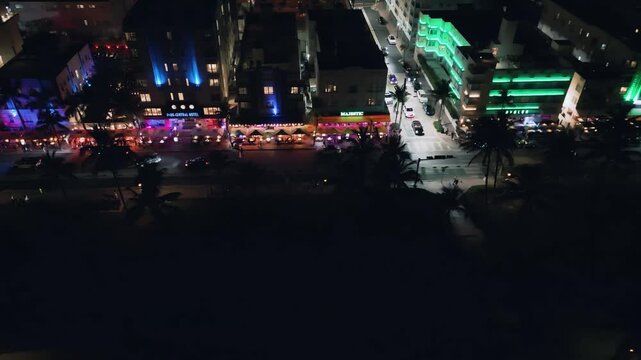 Nighttime aerial view of Collins Avenue's luminous neon architecture and colored lights