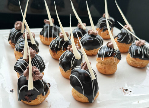 Classic Chocolate Dipped Profiteroles Filled with Cream and White Chocolate Drizzle