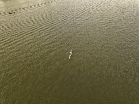 Aerial view of a small wooden canoe with a fisherman on the calm waters of the lagoon in Lekki Phase 1, Lekki, Lagos, Nigeria.