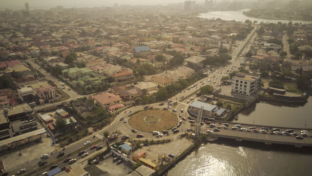 Aerial view of the Lekki Phase 1 roundabout with busy traffic, nearby bridge, and residential buildings in the urban landscape of Lekki, Lagos, Nigeria.