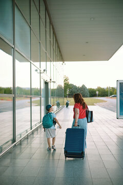Mother and son walking with luggage on airport