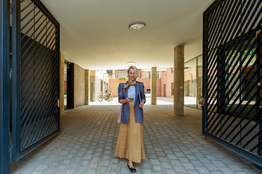 Woman Stands in a Passageway of a Modern Building in the City
