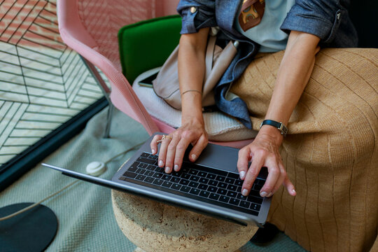 Woman Using Laptop While Sitting in a Modern Cafe Setting