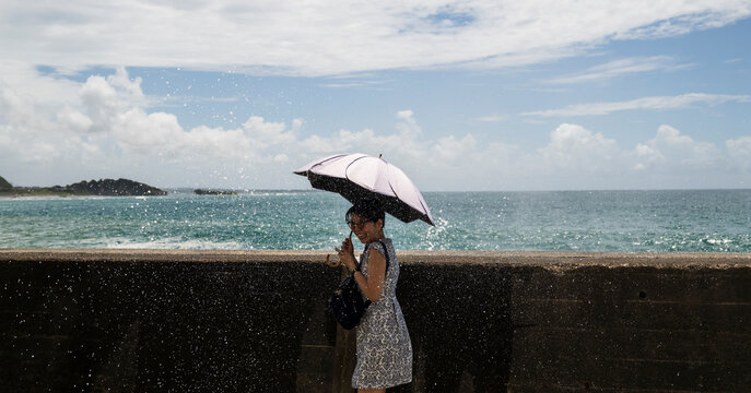 Woman With Parasol Beside Crashing Ocean Waves