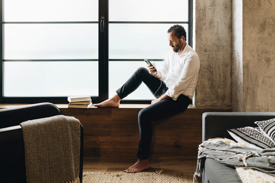 Person relaxing by window listening to music