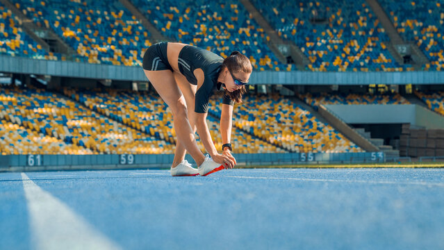 Sportswoman stretching leg before running on stadium track, female athlete warming up for training, fitness workout, healthy lifestyle, endurance and sports preparation concept