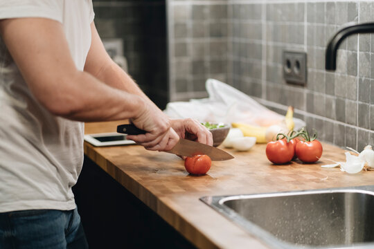 Preparing healthy meal chopping fresh tomatoes in kitchen