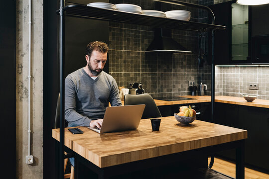 Person working on laptop in modern home kitchen