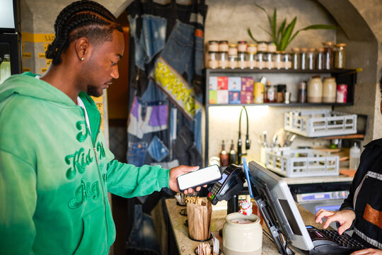 Customer Paying with Smartphone via NFC Terminal at Cafe Counter