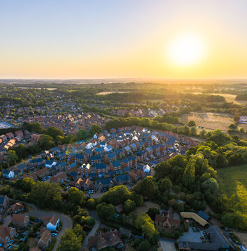 Aerial view of a residential neighborhood with rows of houses surrounded by lush greenery and trees during the golden hour sunset in Hook, England, United Kingdom.