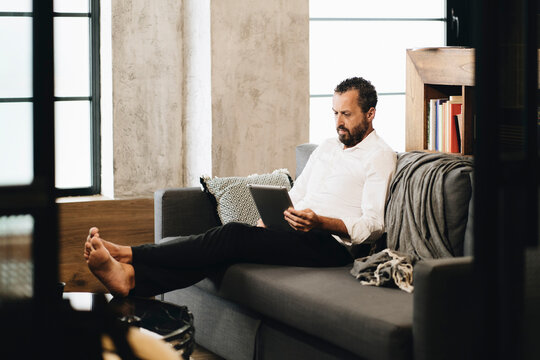 Person relaxing on sofa using digital tablet