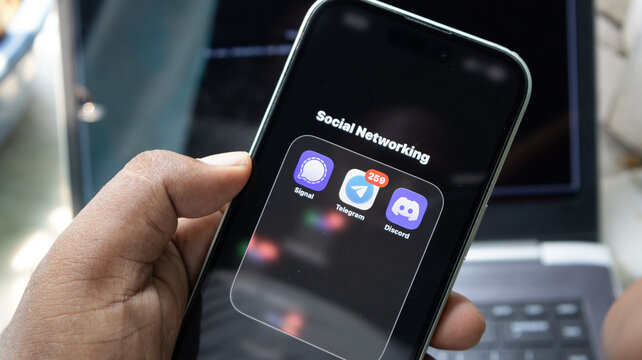 Smartphone showing social networking folder with signal telegram and discord apps on screen.