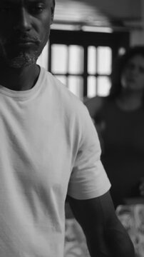 African American husband lost in thought while wife argues in kitchen background