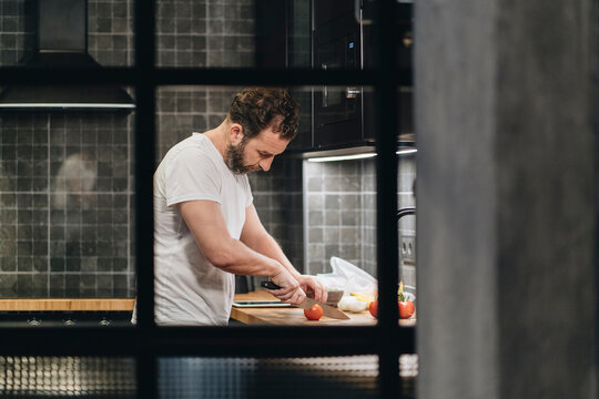 Person cutting tomatoes preparing healthy meal in modern kitchen