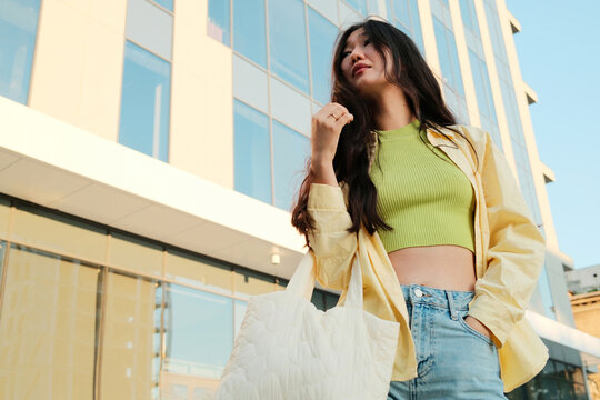 Young stylish asian woman in casual clothes standing in the street