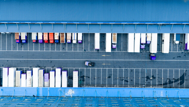 Aerial top view of logistics warehouse with solar rooftops and trucks