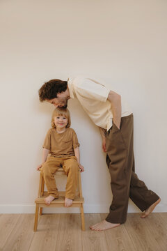 Loving father kisses his little son sitting on a wooden step stool