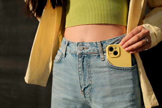 Close up crop of faceless woman holding mobile phone in the pocket