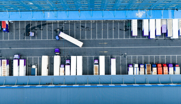 Aerial top view of logistics warehouse with solar rooftops and trucks