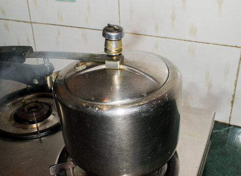 Pressure cooker on a gas stove releasing steam through the pressure regulator