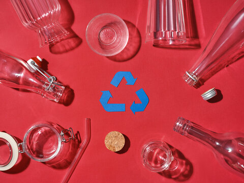 Recycling concept with glass bottles, jars, and a recycling symbol