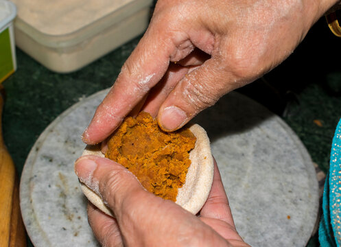 puting mixed sattu in wheat dough for making paratha or roti, old lady hand