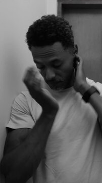 African American man covering face with hands in distress in black and white