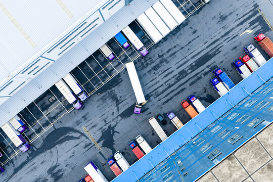 Aerial top view of logistics warehouse with solar rooftops and trucks