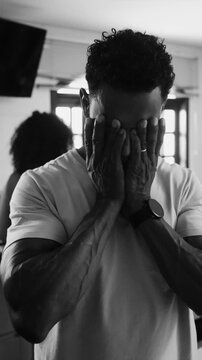 African American father holding head in overwhelm amidst busy kitchen routine