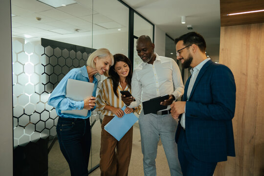 Diverse business team collaborating and discussing in office hallway
