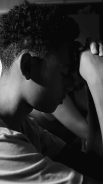 Teenage boy resting head on clasped hands in prayer in black and white