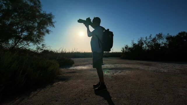 Nature photographer with telephoto camera exploring a natural landscape at golden hour, outdoor adventure, wildlife observation, wilderness exploration, photography hobby and travel