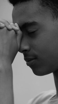 Close-up of teenage boy with eyes closed in devout prayer in black and white