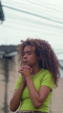 Pensive Hispanic teenage girl clasping hands outdoors while worrying about a problem