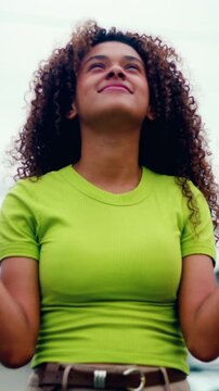 Young Hispanic woman looking up at the sky with hope and faith