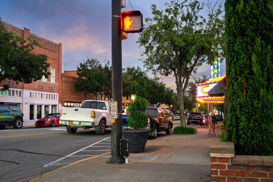 Pedestrians on an early evening walk past shops, cafes and theaters on historic Main Street in the downtown district of the small town of Conway, South Carolina.