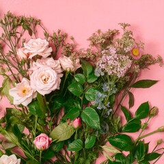 Fototapeta premium Pink roses and wildflowers spill across soft pink background