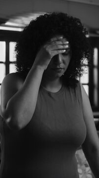 Middle-aged woman holding head in deep anxiety and mental exhaustion in black and white