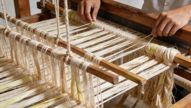 Skilled artisan's hands meticulously weaving natural banana fiber fabric on a traditional wooden loom, demonstrating sustainable textile production for eco-friendly crafts and materials