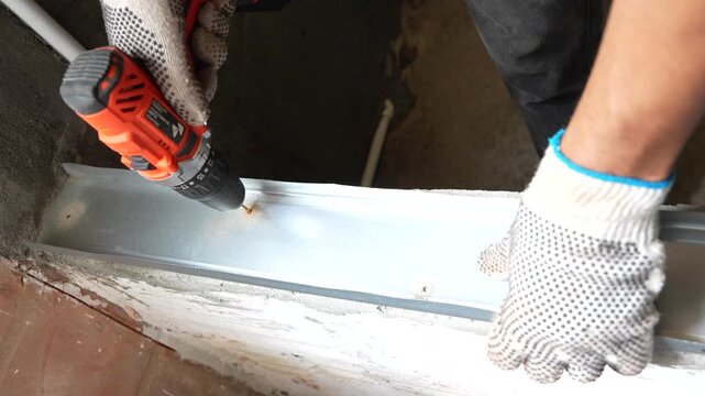 Electric drill making a hole in a metal drywall track