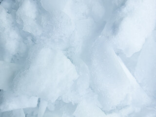 Close-up of crushed ice and dense white snow texture, winter abstract background. © IULIIA
